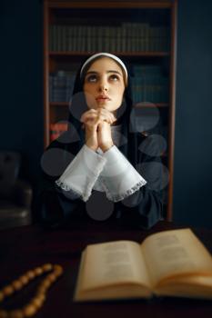 Young nun in a cassock prays crossed her arms. The sister in the monastery, religion and faith, religious people