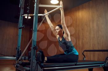 Woman in sportswear doing stretching pilates exercise in gym. Fitness workuot in sport club. Athletic female person, aerobics