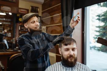 Barber puts mousse on the client 's hair. Professional barbershop is a trendy occupation. Male hairdresser and customer in retro style hair salon