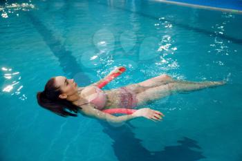 Pregnant woman with big belly swimming in the pool indoors. Pregnancy being, relaxation in the water, recreational exercise for healthcare