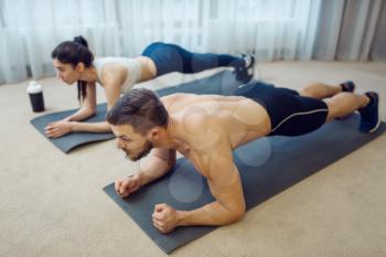 Morning fitness workout of family couple at home. Active man and woman in sportswear doing push up exercise in their house, healthy lifestyle, physical culture