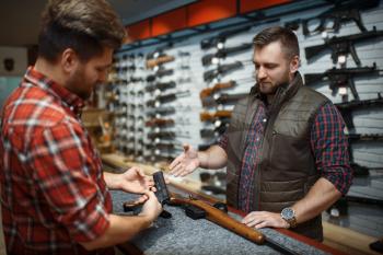Man and owner choosing rifle and handgun in gun shop. Euqipment for hunters in weapon store, hunting and sport shooting hobby, security and selfdefence