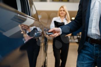 Man and saleswoman choosing auto in car dealership. Customer and seller in vehicle showroom, male person buying transport, automobile dealer business