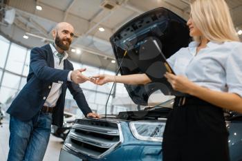 Man and salesgirl choosing auto in car dealership. Customer and seller in vehicle showroom, male person buying transport, automobile dealer business