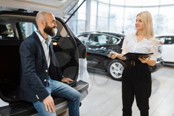 Man and female seller choosing auto in car dealership. Customer and saleswoman in vehicle showroom, male person buying transport, automobile dealer business