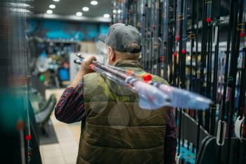 Male angler holds rod with reel in fishing shop. Equipment and tools for fish catching and hunting, accessory choice on showcase in store, spinnings and telescopes assortment