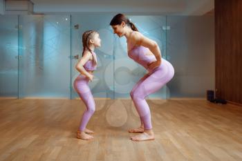 Mother and daughter doing exercise in gym, fitness workout. Mom and little girl in sportswear, joint training in sportclub