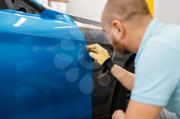 Male car wrapper hands installs protective vinyl foil or film on vehicle door. Worker makes auto detailing. Automobile paint protection, professional tuning