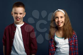 Little boy and girl making faces in studio. Happy childhood, children having fun, funny kids isolated on dark background, child emotion