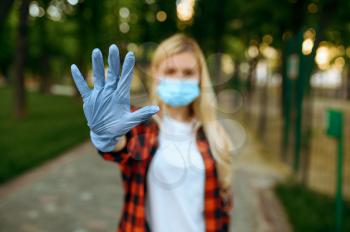 Young woman in mask and gloves in park, quarantine. Female person walking during the epidemic, health care and protection, pandemic lifestyle