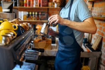 Male barista in apron prepares aroma coffee in cafe. Man makes fresh espresso in cafeteria