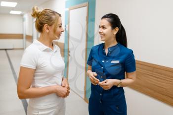 Two female doctors talking in clinic hall, surgery and stomatology. Medical workers in uniform, medicine and health, professional healthcare in hospital