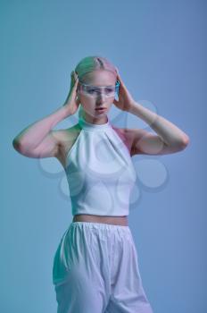 Attractive futuristic woman in white clothes and modern glasses, grey background. Sexy female person in virtual reality style, future technology, futurism concept