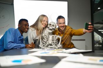 Funny managers, selfie with skeleton, conference in IT office, joke. Professional teamwork and planning, group brainstorming and corporate work, meeting of colleagues
