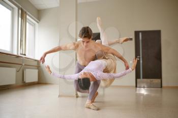 Couple of ballet dancers, dancing in action. Ballerina with partner training in class, dance studio interior on background