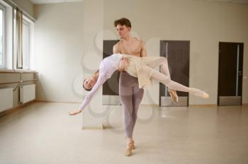 Couple of ballet dancers, dancing in action. Ballerina with partner training in class, dance studio interior on background