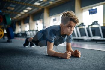 Boy doing push up exercise on the floor in gym. Youngster on training in sport club, healthcare and healthy lifestyle, schoolboy on workout, sportive youth