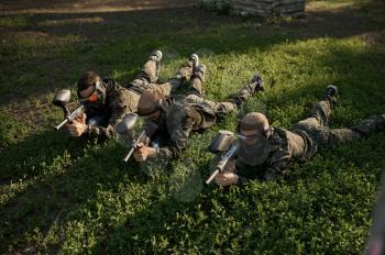 Paintball team in masks, battle on playground in the forest. Extreme sport with pneumatic weapon and paint bullets or markers, military game outdoors, combat tactics