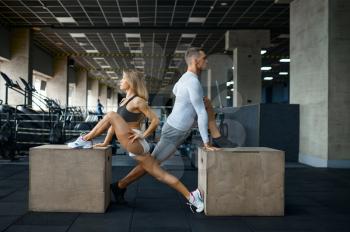 Slim couple doing exercise on cubes in gym. Athletic man and woman on workout in sport club, active healthy lifestyle, physical wellness