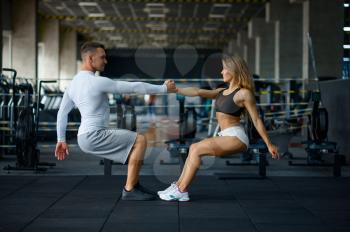 Happy sportive couple doing push-ups, training in gym. Athletic man and woman on workout in sport club, active lifestyle