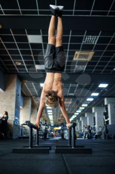 Athletic boy doing exercise on uneven bars in gym. Youngster on training in sport club, healthcare and healthy lifestyle, schoolboy on aerobics workout, sportive youth