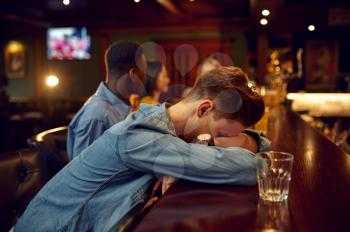 Friends drinks beer, man sleeps at the counter in bar. Group of people relax in pub, night lifestyle, friendship