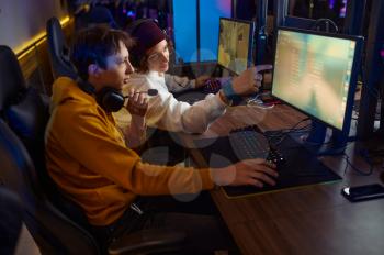 Two gamers in headsets play in game club. Virtual entertainment, e-sport tournament, cybersport lifestyle. Male person leisures in internet cafe