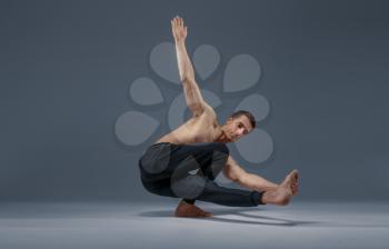 Yoga doing stretching exercise in studio, grey background. Strong man practicing yogi , asana training, top concentration, healthy lifestyle