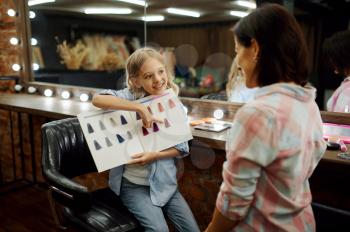 Mother and daughter having fun in make-up salon. Mom and little girl play stylists together, happy family