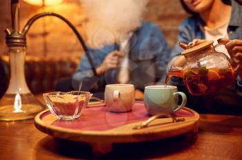 Love couple leisures and drinks tea in hookah bar. Shisha smoking, traditional smoke culture, tobacco aroma for relaxation, rest with bong