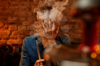 Young man relax in hookah bar, hooka smoke. Shisha smoking, traditional bong culture, tobacco aroma for relaxation, rest with hooka