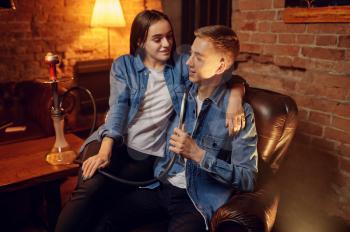 Young love couple relax in hookah bar, hooka chill out. Shisha smoking, traditional bong culture, tobacco aroma for relaxation, rest with hooka