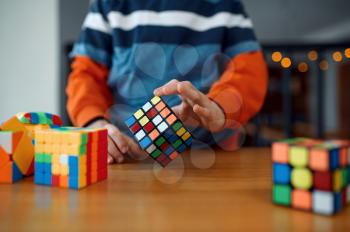 Little boy holds puzzle cube, selective focus on hand. Toy for brain and logical mind training, creative game, solving of complex problems