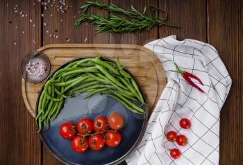 Fresh tomatoes and green beans in pods on wooden background. Organic vegetarian food, grocery products, healthy lifestyle concept