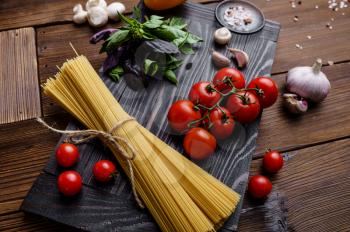 Fresh vegetables and spaghetti on wooden background. Organic vegetarian food, grocery assortment, natural products, healthy lifestyle concept