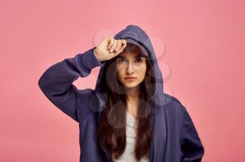Young cute woman in hoodie, pink background, emotion. Face expression, female person looking on camera in studio, emotional concept, feelings