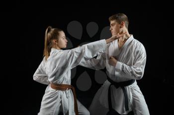 Female karate fighter on training with master, white kimono, dark smoky background. Karateka on workout, martial arts, fighting