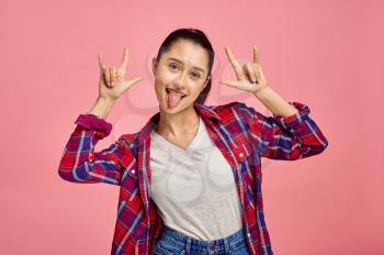 Smiling woman shows her tongue, pink background, emotion. Face expression, female person looking on camera in studio, emotional concept, feelings