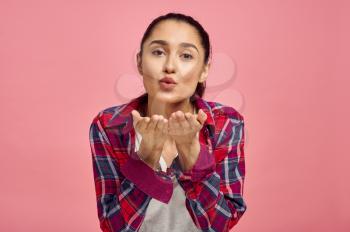 Cute woman blows a kiss, pink background, emotion. Face expression, female person looking on camera in studio, emotional concept, feelings