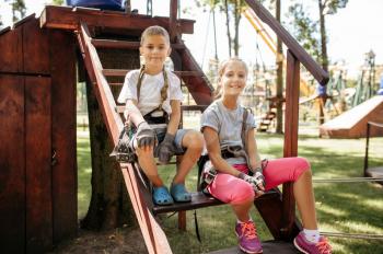 Little girl and boy sitting on stairs in rope park. Children climbing on suspension bridge, extreme sport adventure on vacations, danger entertainment outdoors