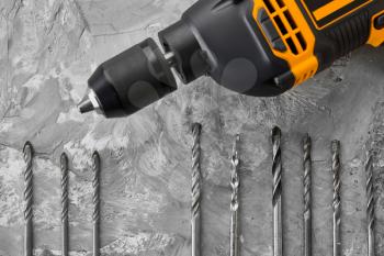 Set of borers and electric drill, concrete background, nobody. Professional instrument, builder equipment, drilling tools