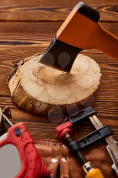 Axe on stump, measuring tape and vise, wooden background, top view, nobody. Professional instrument, carpenter equipment, woodworker tools