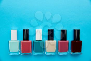Nail care products, row of polish in bottles on blue background, nobody. Healthcare procedures concept, fashion cosmetic, manicure and pedicure tools, fingernail varnish