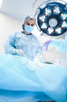Female surgeon and assistant, professional surgery, operating room. Doctor in uniform performs operation, medical clinic worker, surgical medicine and health, healthcare in hospital