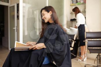 Female customer at the mirror in hairdressing salon. Stylist and client in hairsalon. Beauty business, professional service