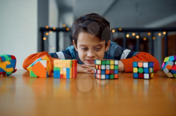 Little boy looks on puzzle cubes. Toy for brain and logical mind training, creative game, solving of complex problems