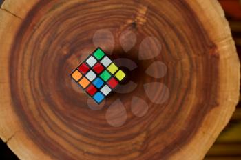 Classical colorful puzzle cube on wooden stump, closeup view, nobody. Toy for brain and logical mind training, creative game, solving of complex problems