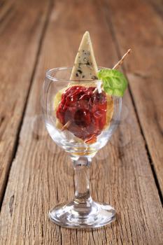 Dried tomato and piece of blue cheese in stemmed glass