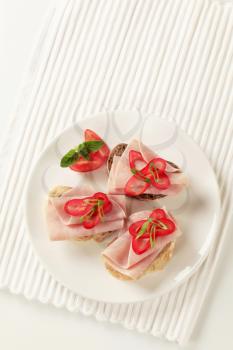 Open faced ham sandwiches garnished with red pepper