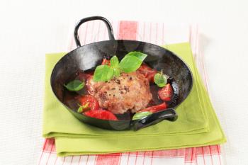 Meat patty and tomatoes on a frying pan